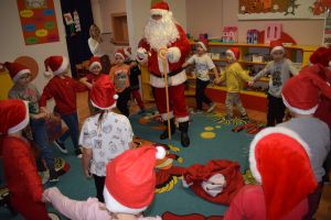 Mikołaj odwiedzający uczniów i przedszkolaków i częstujący ich słodyczami z czerwonego worka