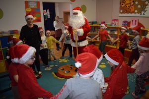 Mikołaj odwiedzający uczniów i przedszkolaków i częstujący ich słodyczami z czerwonego worka