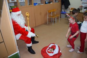 Mikołaj odwiedzający uczniów i przedszkolaków i częstujący ich słodyczami z czerwonego worka