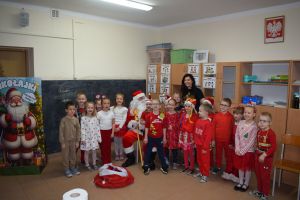 Mikołaj odwiedzający uczniów i przedszkolaków i częstujący ich słodyczami z czerwonego worka
