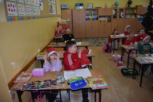 Mikołaj odwiedzający uczniów i przedszkolaków i częstujący ich słodyczami z czerwonego worka