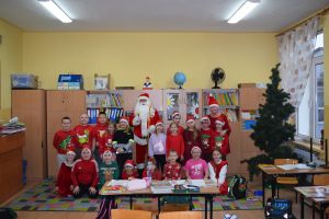 Mikołaj odwiedzający uczniów i przedszkolaków i częstujący ich słodyczami z czerwonego worka