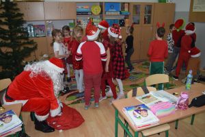 Mikołaj odwiedzający uczniów i przedszkolaków i częstujący ich słodyczami z czerwonego worka