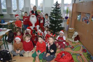 Mikołaj odwiedzający uczniów i przedszkolaków i częstujący ich słodyczami z czerwonego worka