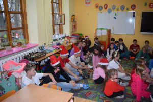 Mikołaj odwiedzający uczniów i przedszkolaków i częstujący ich słodyczami z czerwonego worka