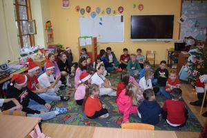 Mikołaj odwiedzający uczniów i przedszkolaków i częstujący ich słodyczami z czerwonego worka