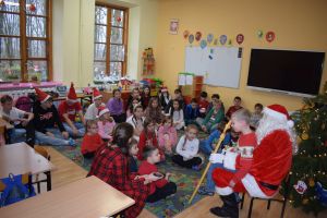 Mikołaj odwiedzający uczniów i przedszkolaków i częstujący ich słodyczami z czerwonego worka