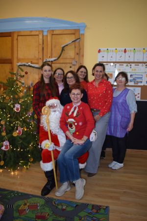 Mikołaj odwiedzający uczniów i przedszkolaków i częstujący ich słodyczami z czerwonego worka