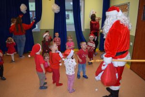 Mikołaj odwiedzający uczniów i przedszkolaków i częstujący ich słodyczami z czerwonego worka