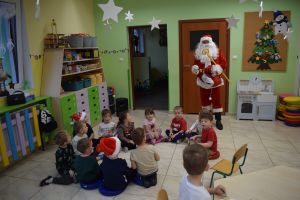 Mikołaj odwiedzający uczniów i przedszkolaków i częstujący ich słodyczami z czerwonego worka