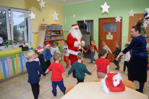 Mikołaj odwiedzający uczniów i przedszkolaków i częstujący ich słodyczami z czerwonego worka