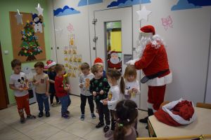 Mikołaj odwiedzający uczniów i przedszkolaków i częstujący ich słodyczami z czerwonego worka