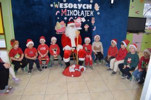 Mikołaj odwiedzający uczniów i przedszkolaków i częstujący ich słodyczami z czerwonego worka