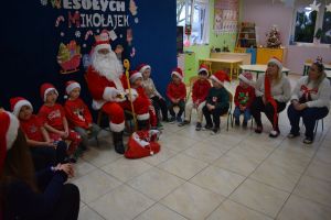 Mikołaj odwiedzający uczniów i przedszkolaków i częstujący ich słodyczami z czerwonego worka