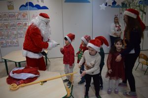 Mikołaj odwiedzający uczniów i przedszkolaków i częstujący ich słodyczami z czerwonego worka