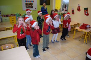 Mikołaj odwiedzający uczniów i przedszkolaków i częstujący ich słodyczami z czerwonego worka