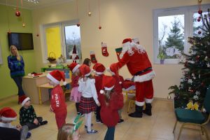 Mikołaj odwiedzający uczniów i przedszkolaków i częstujący ich słodyczami z czerwonego worka