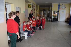 Mikołaj odwiedzający uczniów i przedszkolaków i częstujący ich słodyczami z czerwonego worka