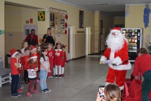 Mikołaj odwiedzający uczniów i przedszkolaków i częstujący ich słodyczami z czerwonego worka