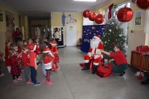 Mikołaj odwiedzający uczniów i przedszkolaków i częstujący ich słodyczami z czerwonego worka