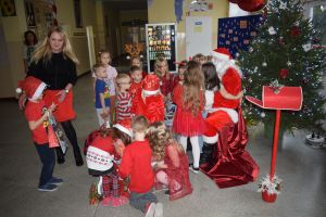 Mikołaj odwiedzający uczniów i przedszkolaków i częstujący ich słodyczami z czerwonego worka