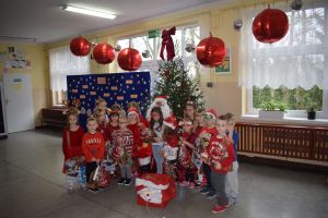 Mikołaj odwiedzający uczniów i przedszkolaków i częstujący ich słodyczami z czerwonego worka