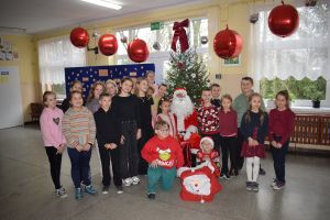 Mikołaj odwiedzający uczniów i przedszkolaków i częstujący ich słodyczami z czerwonego worka