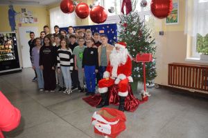 Mikołaj odwiedzający uczniów i przedszkolaków i częstujący ich słodyczami z czerwonego worka