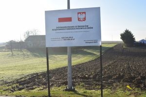 Tablica informująca o wykonanej inwestycji, zainstalowana przy drodze - modernizacja drogi w Kisielewie