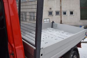 Czerwony samochód dostawczy w wywrotką na tle budynku