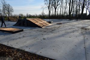 Betonowy plac w parku, na nim powstające elementy skateparku