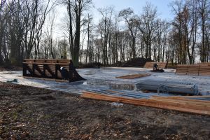 Betonowy plac w parku, na nim powstające elementy skateparku