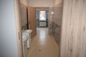 Korytarz jednej z wyremontowanych łazienek, z ujęciem na nowe umywalki z szafkami