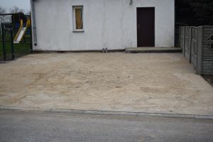Ułożona nowa kostka brukowa, posypana piaskiem, na tle budynku świetlicy w Zbyszewie