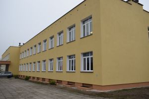 Boczna część wyremontowanej szkoły,pokryta nową elewacją, w kolorze ciemnej żółci