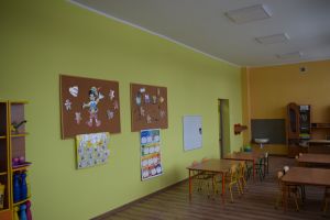 Sala lekcyjna w kolorze ścian zielono-żółtym wraz z wyposażeniem-ławki, krzesła, szafki